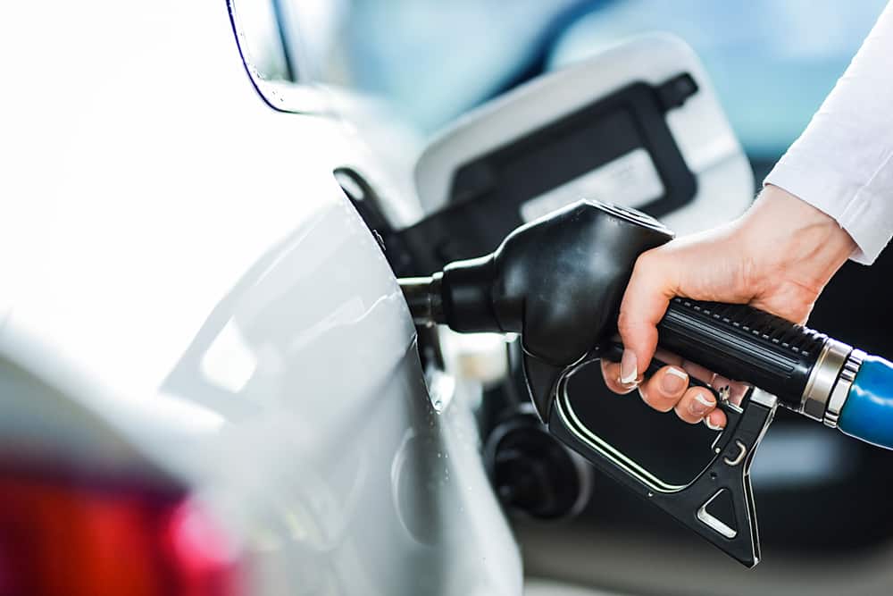 Woman pumping petrol at gas station into vehicle.