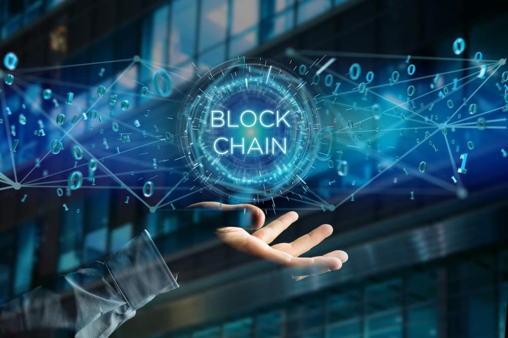 View of a Blockchain title with 0 and 1 data flying over. Production Perig / Shutterstock.com
